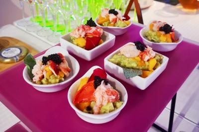 Façade illuminée d'un bâtiment élégant au crépuscule, avec un jardin et des invités rassemblés devant.