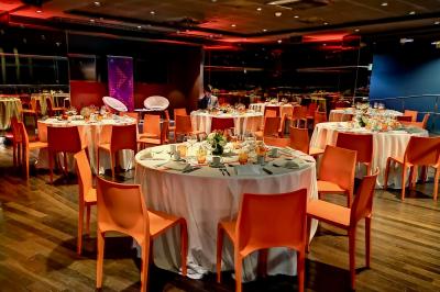 Façade illuminée d'un bâtiment élégant au crépuscule, avec un jardin et des invités rassemblés devant.