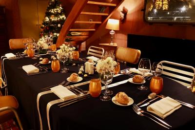 Façade illuminée d'un bâtiment élégant au crépuscule, avec un jardin et des invités rassemblés devant.