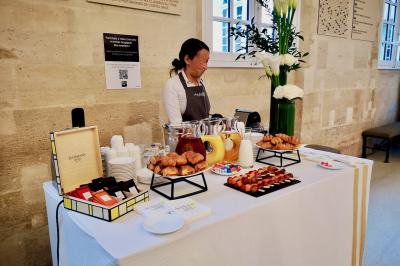 Façade illuminée d'un bâtiment élégant au crépuscule, avec un jardin et des invités rassemblés devant.
