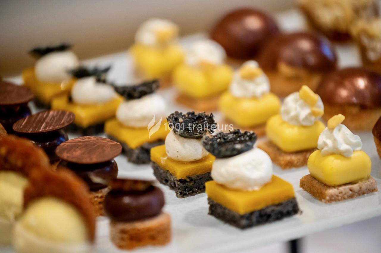 Assortiment de petits desserts élégants, incluant des bouchées au citron, au chocolat et à la crème, présentés sur un…