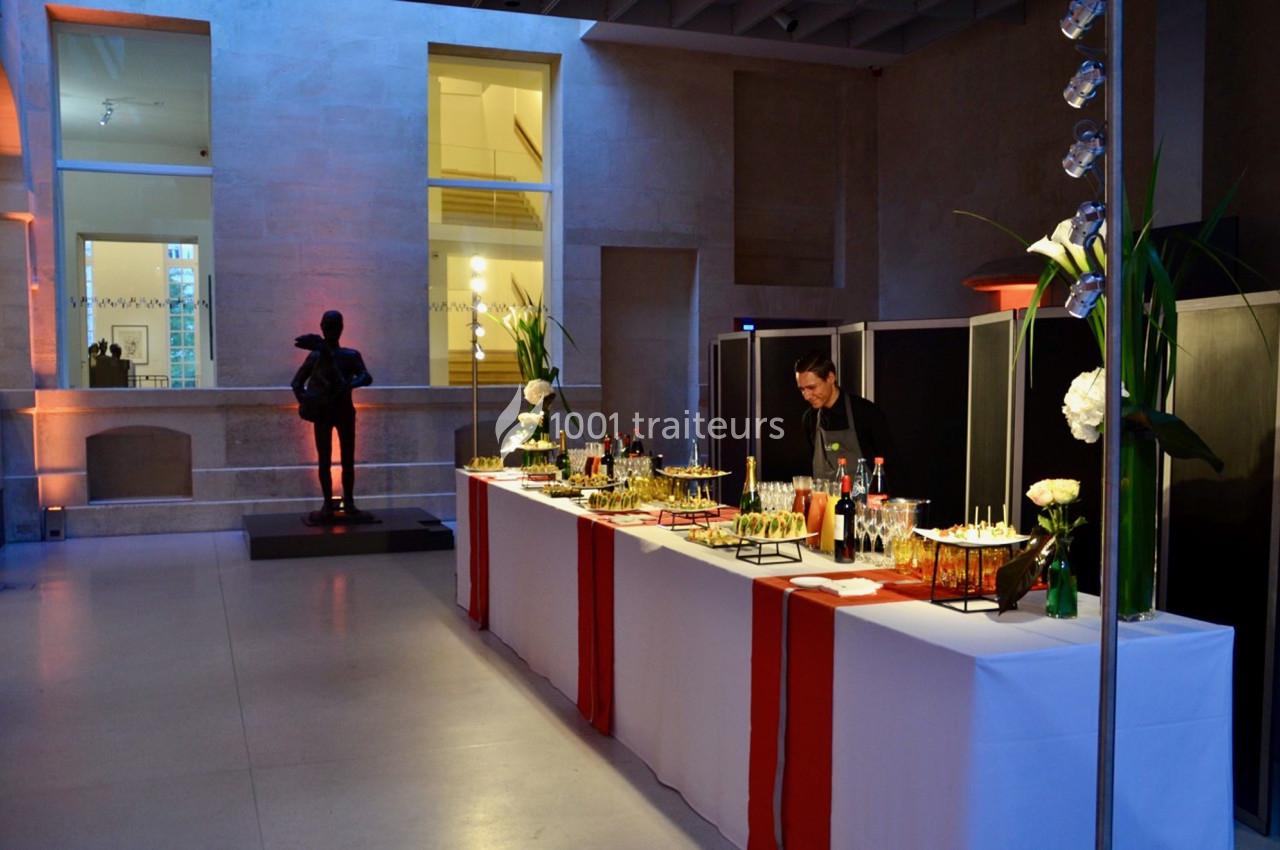Buffet élégant avec boissons et amuse-bouches dans un espace intérieur moderne, éclairé par une lumière tamisée.