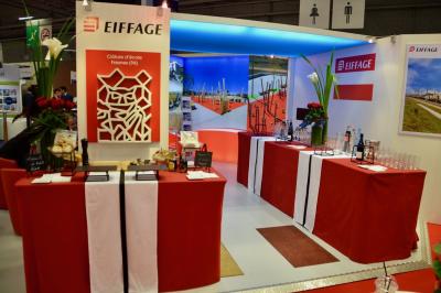 Façade illuminée d'un bâtiment élégant au crépuscule, avec un jardin et des invités rassemblés devant.