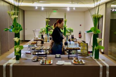 Façade illuminée d'un bâtiment élégant au crépuscule, avec un jardin et des invités rassemblés devant.