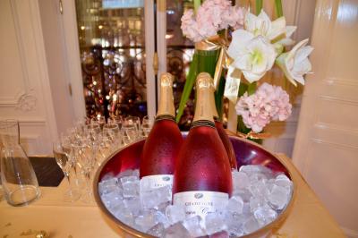 Deux bouteilles de champagne rosé dans un seau rempli de glace, entourées de fleurs et de verres à pied.