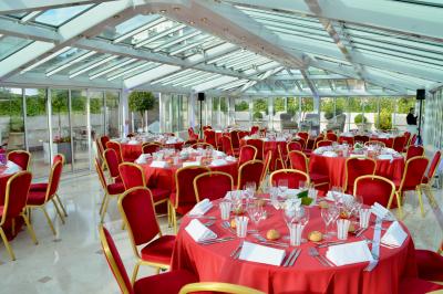 Façade illuminée d'un bâtiment élégant au crépuscule, avec un jardin et des invités rassemblés devant.