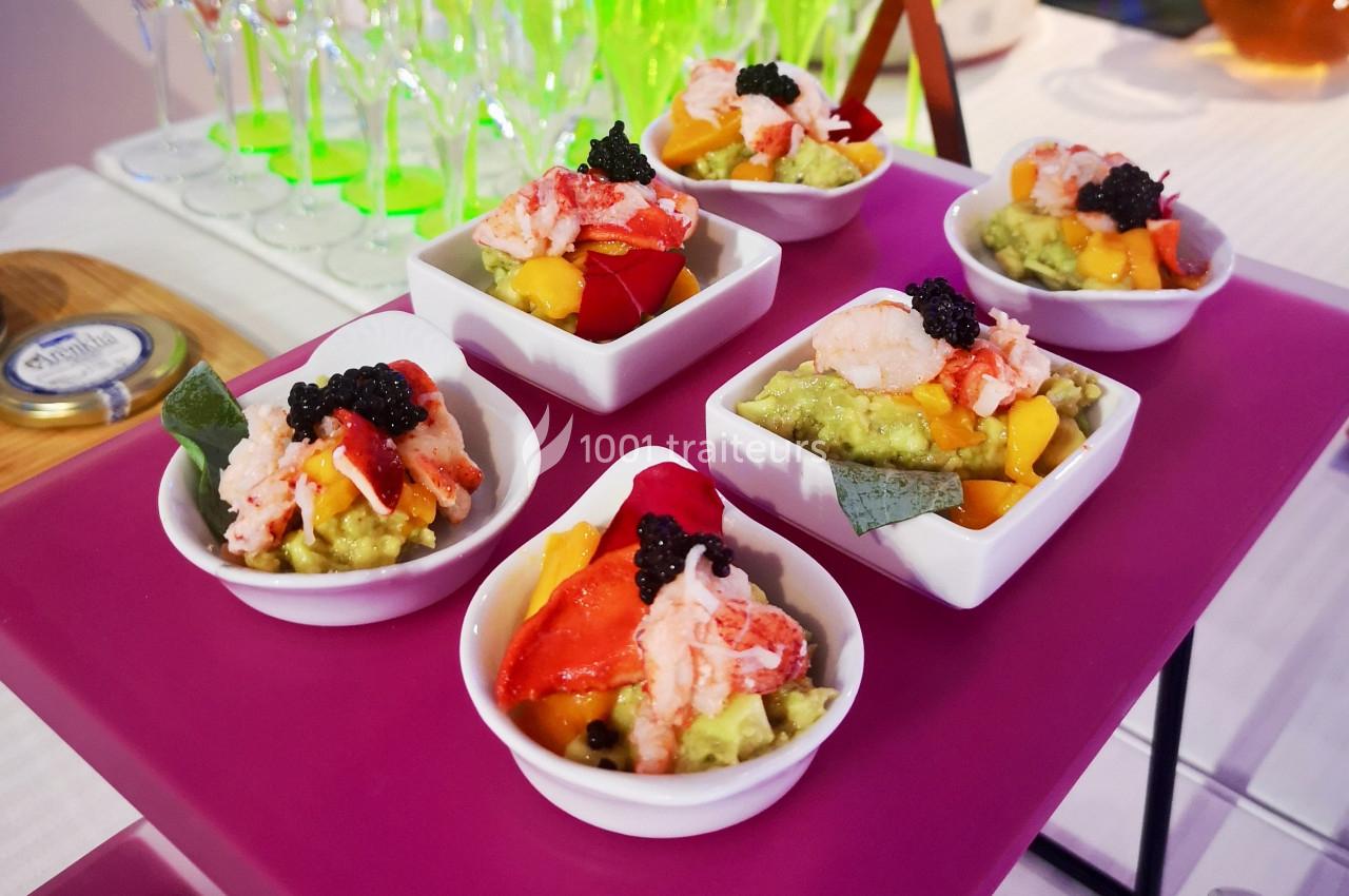 Cinq verrines colorées contenant avocat, mangue, chair de crabe, œufs de poisson et herbes, présentées sur un plateau rose.