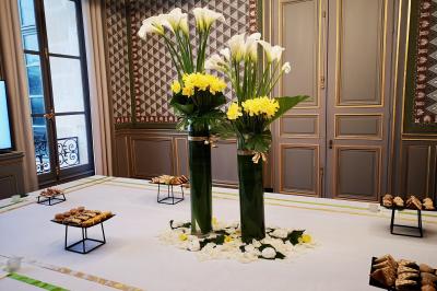 Façade illuminée d'un bâtiment élégant au crépuscule, avec un jardin et des invités rassemblés devant.