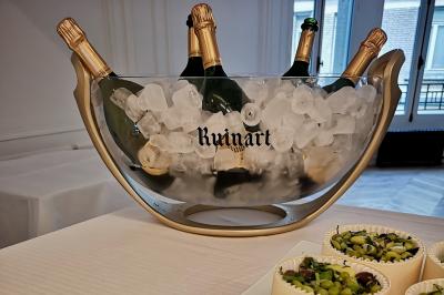 Façade illuminée d'un bâtiment élégant au crépuscule, avec un jardin et des invités rassemblés devant.