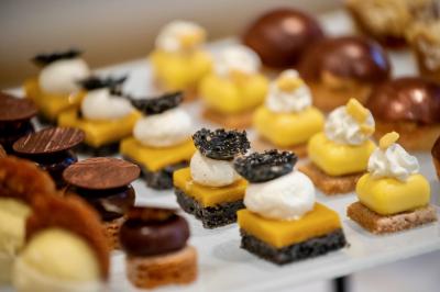 Façade illuminée d'un bâtiment élégant au crépuscule, avec un jardin et des invités rassemblés devant.