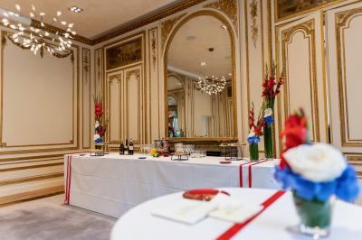 Façade illuminée d'un bâtiment élégant au crépuscule, avec un jardin et des invités rassemblés devant.