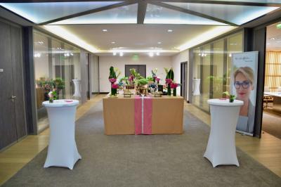 Façade illuminée d'un bâtiment élégant au crépuscule, avec un jardin et des invités rassemblés devant.