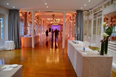Façade illuminée d'un bâtiment élégant au crépuscule, avec un jardin et des invités rassemblés devant.