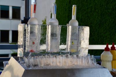 Façade illuminée d'un bâtiment élégant au crépuscule, avec un jardin et des invités rassemblés devant.