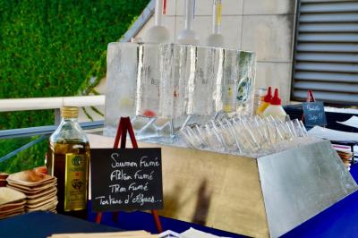 Façade illuminée d'un bâtiment élégant au crépuscule, avec un jardin et des invités rassemblés devant.