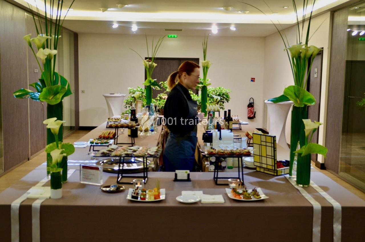 Table de buffet élégamment dressée avec divers plats et boissons, décorée de fleurs blanches, dans une salle lumineuse.