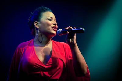 Femme aux cheveux attachés regardant l'objectif, éclairage naturel et arrière-plan flou.