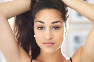 Femme aux cheveux attachés regardant l'objectif, éclairage naturel et arrière-plan flou.