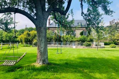 Chambre mansardée avec mur en briques, lit avec coussins, parquet clair et lumière naturelle provenant de deux fenêtres de…