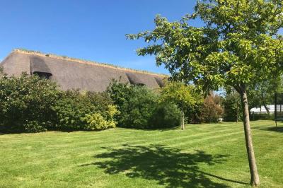 Chambre mansardée avec mur en briques, lit avec coussins, parquet clair et lumière naturelle provenant de deux fenêtres de…