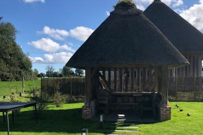 Chambre mansardée avec mur en briques, lit avec coussins, parquet clair et lumière naturelle provenant de deux fenêtres de…