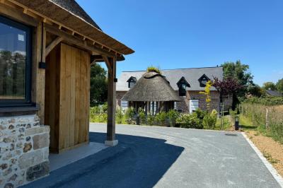Chambre mansardée avec mur en briques, lit avec coussins, parquet clair et lumière naturelle provenant de deux fenêtres de…
