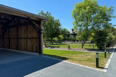 Chambre mansardée avec mur en briques, lit avec coussins, parquet clair et lumière naturelle provenant de deux fenêtres de…