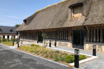 Chambre mansardée avec mur en briques, lit avec coussins, parquet clair et lumière naturelle provenant de deux fenêtres de…