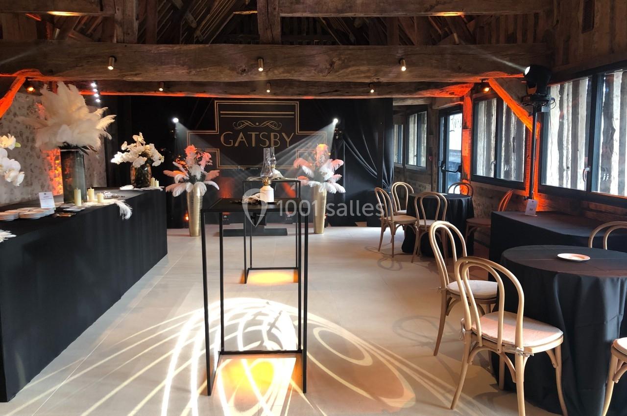 Salle décorée dans un style élégant avec des tables, des chaises en bois, des plumes blanches et un panneau ’Gatsby’.