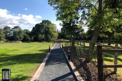 Chambre mansardée avec mur en briques, lit avec coussins, parquet clair et lumière naturelle provenant de deux fenêtres de…