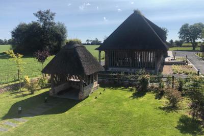 Chambre mansardée avec mur en briques, lit avec coussins, parquet clair et lumière naturelle provenant de deux fenêtres de…