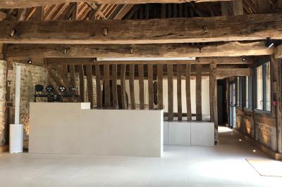 Chambre mansardée avec mur en briques, lit avec coussins, parquet clair et lumière naturelle provenant de deux fenêtres de…