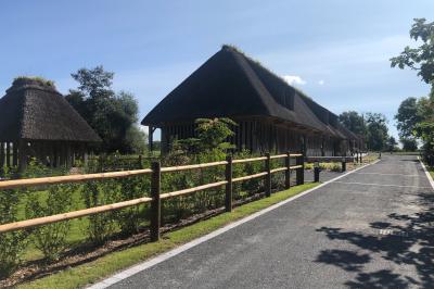 Chambre mansardée avec mur en briques, lit avec coussins, parquet clair et lumière naturelle provenant de deux fenêtres de…
