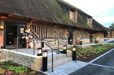 Chambre mansardée avec mur en briques, lit avec coussins, parquet clair et lumière naturelle provenant de deux fenêtres de…