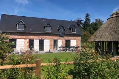 Chambre mansardée avec mur en briques, lit avec coussins, parquet clair et lumière naturelle provenant de deux fenêtres de…