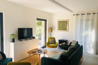 Chambre mansardée avec mur en briques, lit avec coussins, parquet clair et lumière naturelle provenant de deux fenêtres de…