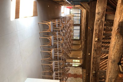 Chambre mansardée avec mur en briques, lit avec coussins, parquet clair et lumière naturelle provenant de deux fenêtres de…