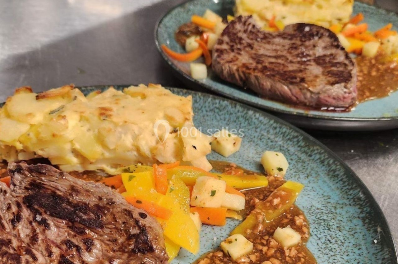Assiette contenant un steak grillé, gratin de pommes de terre et légumes colorés, servie avec une sauce brune.