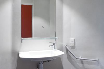 Douche accessible avec barre d'appui, siège rabattable et pommeau de douche réglable.