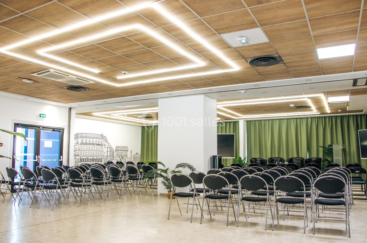 Salle de conférence lumineuse avec des rangées de chaises noires, un plafond en bois et des rideaux verts.