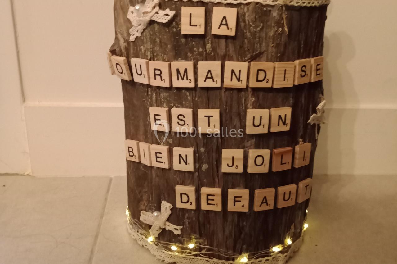 Bûche décorative ornée de lettres en bois formant une phrase et de sucettes colorées plantées sur le dessus.