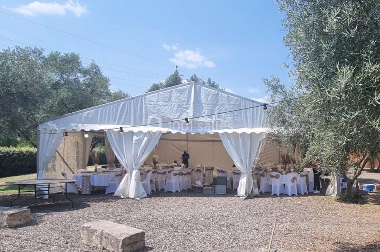 Tente blanche installée en extérieur, aménagée avec des tables et chaises pour un événement.