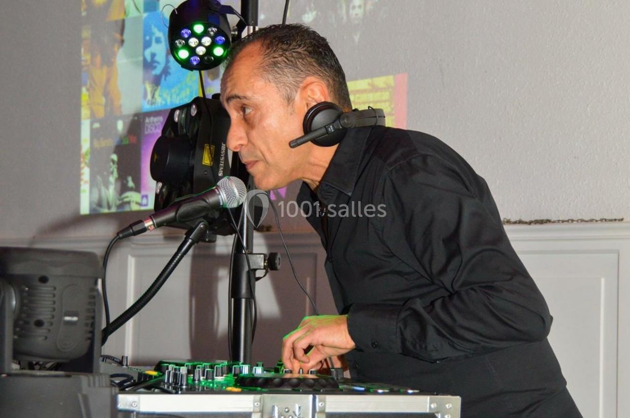 Un DJ mixant de la musique sur une console, portant un casque et parlant dans un micro, avec des lumières colorées en…