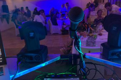 Table de mixage avec platines, microphones et panneau lumineux indiquant ’DJ Olivier’ sur une table en bois.