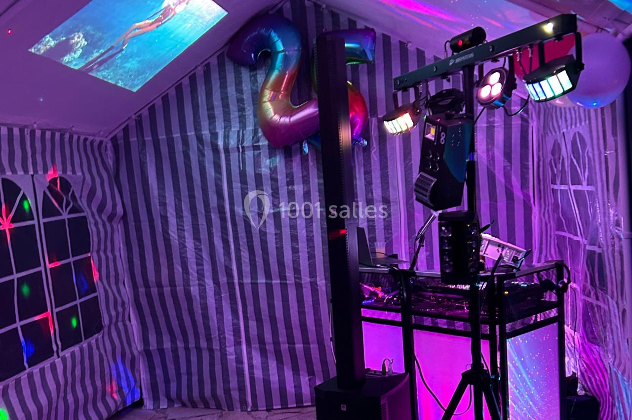 Installation de matériel de son et lumière dans une tente décorée pour une fête, avec un ballon en forme de ’25’.