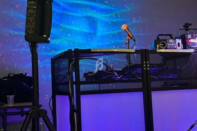 Poste de DJ avec éclairage coloré, microphone sur pied et équipement audio installé sur une table rétroéclairée.