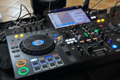 Console de mixage DJ avec casque, micro et ordinateur portable affichant une image sous-marine, sur un sol carrelé.