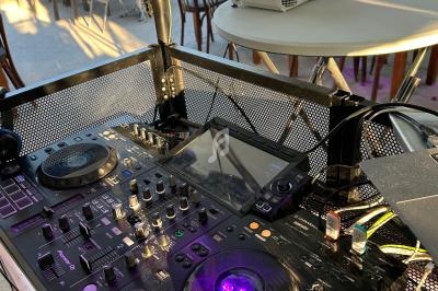 Table de mixage DJ avec platines et écran tactile, installée en extérieur près de tables et chaises sous un éclairage…