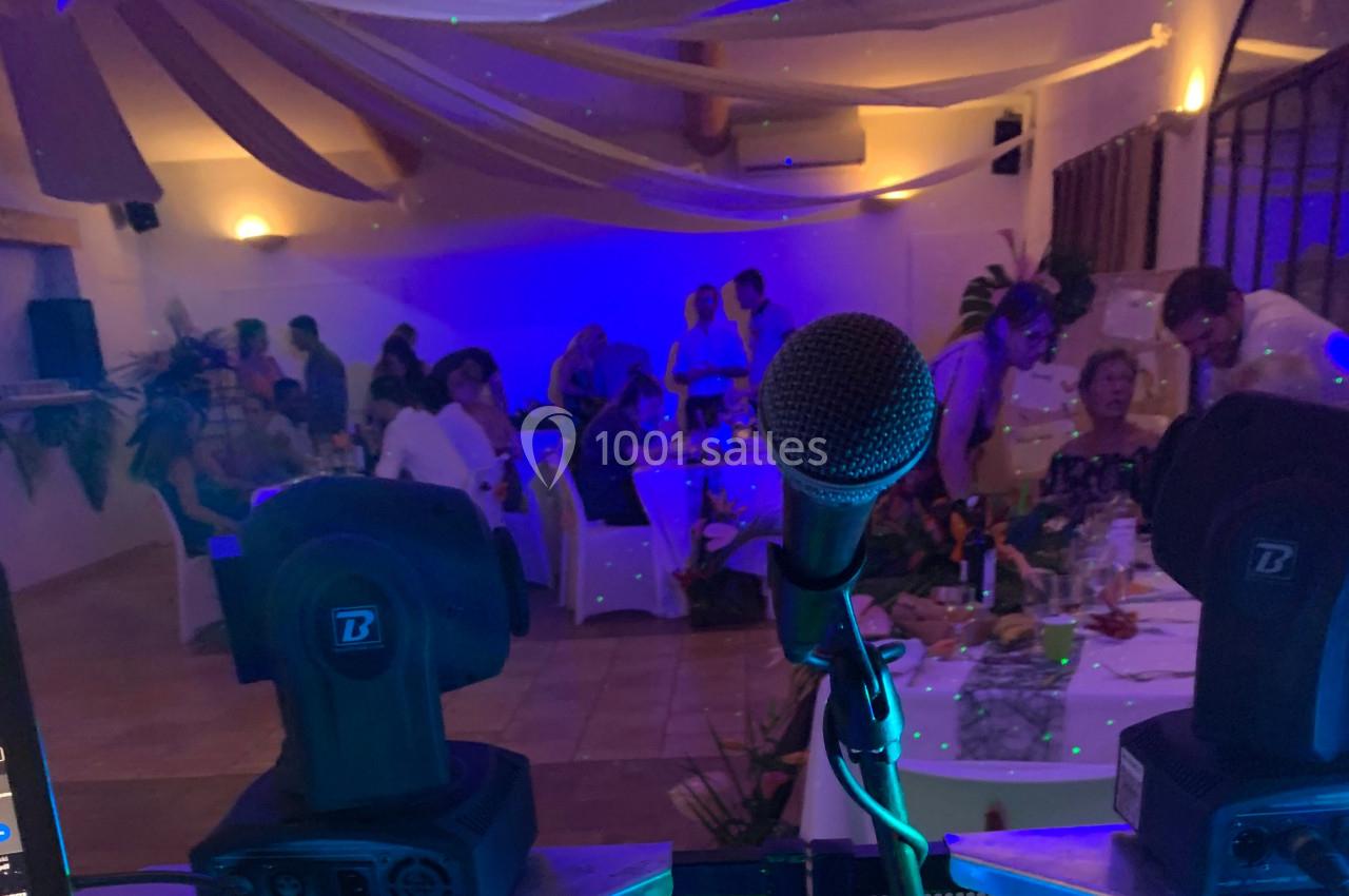 Vue depuis une scène avec un microphone et des lumières, face à des invités assis dans une salle décorée pour un événement.