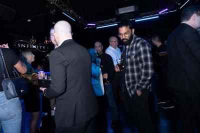 Entrée d'un club nocturne avec enseigne lumineuse ’Infinity Club’ et porte ornée de motifs décoratifs.